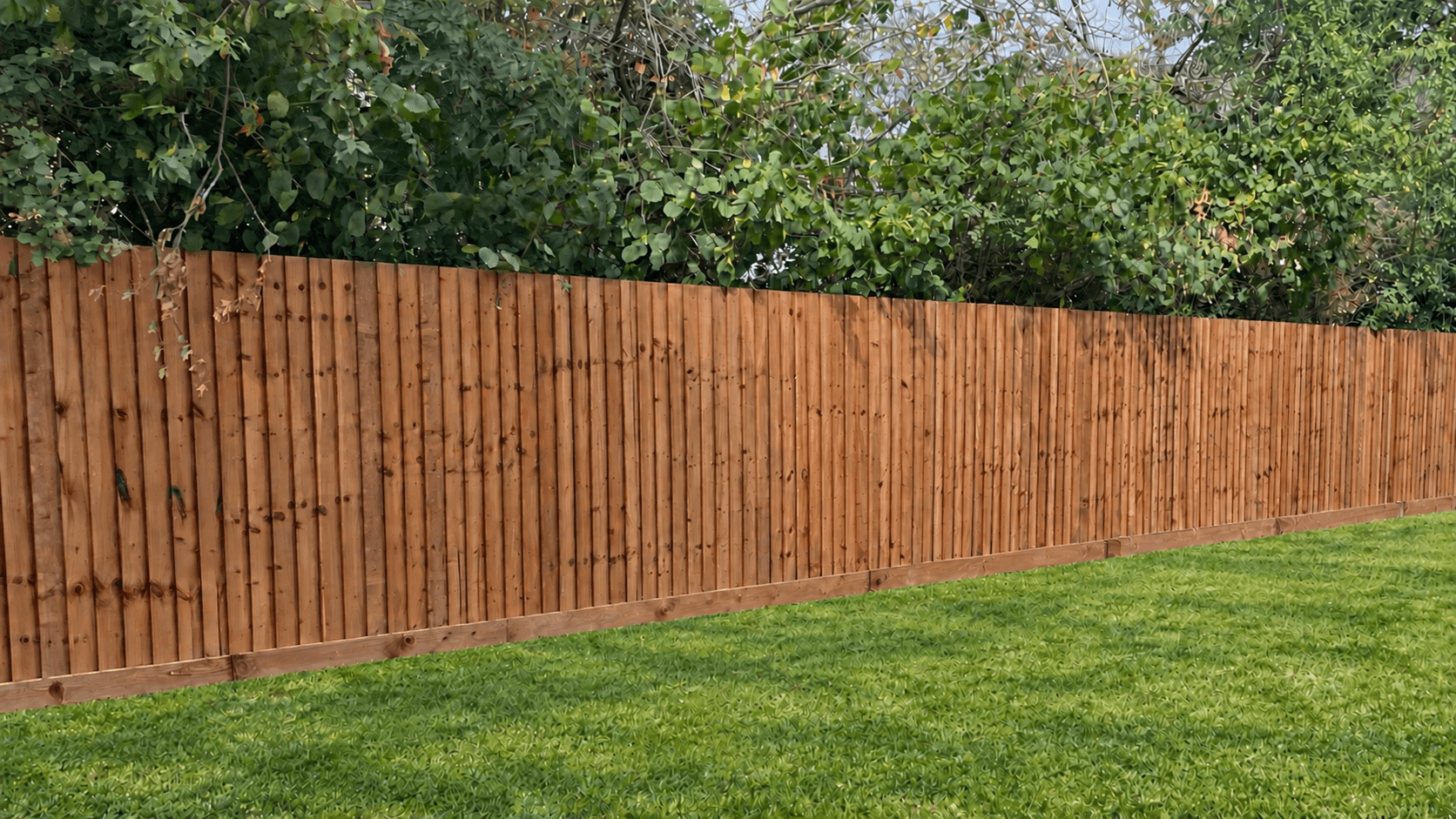 Compare the Best Garden Fence Types in the UK: From Closeboard to Lap Panels 1 Continuous closeboard fencing with vertical featheredge boards above a timber gravel board